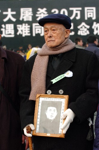 12月13日,遇難者遺屬程銘政手捧在南京大屠殺中遇難父親程長河的照片參加悼念活動。
