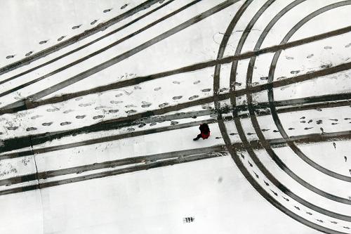12月29日,山東省臨沂市郯城縣一名行人行走在車輛壓過的雪地上。新華社發(fā)(張春雷 攝)