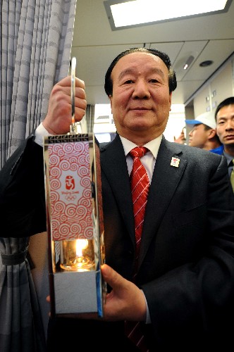 4月5日,北京奧組委執(zhí)行副主席蔣效愚手持火種燈準(zhǔn)備走出機(jī)艙。 新華社記者 周文杰 攝