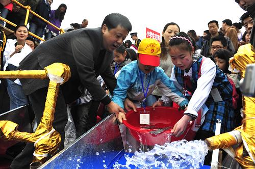 4月8日,兩名學(xué)生將人工繁育的“子二代”中華鱘魚苗放歸長江。新華社發(fā)(肖佳法 攝)
