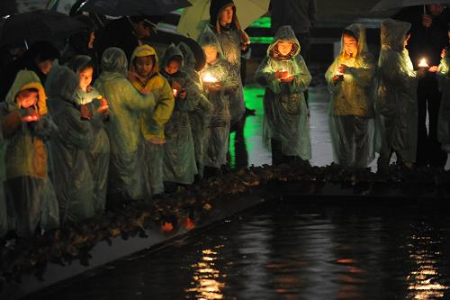 12月12日,參加儀式的小學生代表冒雨點燃手中的紅燭。新華社記者 韓瑜慶 攝