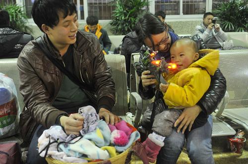 1月20日晚,在杭州火車站候車廳,來自貴州遵義的1歲半男孩何志博在母親的懷里把玩特意帶回家過年的玩具槍,他們將乘坐L199次列車返鄉(xiāng)。新華社記者 黃宗治 攝