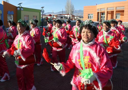 2月5日,新疆哈密市沁城鄉(xiāng)城東村村民在“安居富民房”前打腰鼓。新華社發(fā)(蔡增樂(lè) 攝)