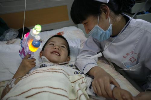 4月16日,在襄陽市第一人民醫(yī)院病房,獲救的4歲男童與護(hù)士玩耍。4月8日,湖北省襄陽市一名四歲的男童在玩耍中被一塊銳利的玻璃刺中右頸部,造成頸部總動脈斷裂,被送至襄陽市第一人民醫(yī)院時已失去了體內(nèi)三分之二的血液,處于嚴(yán)重休克狀態(tài)。醫(yī)院迅速開通綠色通道,對其進(jìn)行搶救。經(jīng)過醫(yī)護(hù)人員的不懈努力,相繼輸血1350余毫升,男孩終于脫離生命危險。目前,男孩身體在逐步康復(fù)中。據(jù)襄陽一院外科主任李德勝介紹,四歲男孩體內(nèi)的血液量通常為1500毫升,失血如此多的男童能夠被挽救過來,在他從業(yè)20多年的經(jīng)歷中還是第一次碰到,非常難得。新華社發(fā)(龔波 攝)