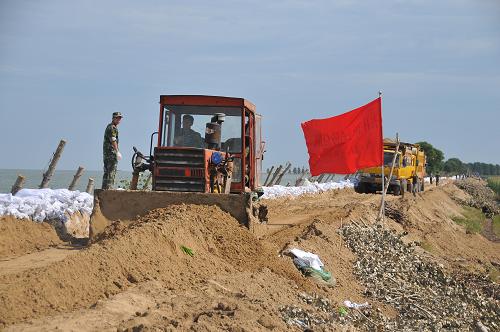 8月21日,武警官兵及當(dāng)?shù)厝罕娫谠铝僚菟畮?kù)6號(hào)壩上鋪墊沙土加固大堤。 新華社發(fā)(劉碩 攝)