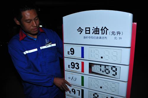 9月30日零時(shí)許,河北保定一家加油站的工作人員在調(diào)整油價(jià)公告牌。新華社記者 朱旭東 攝