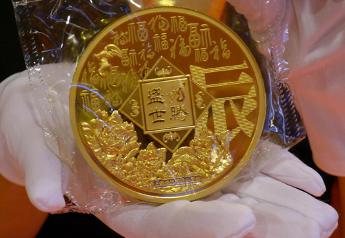 工作人員在展示一枚“龍年生肖金章”(背面)。