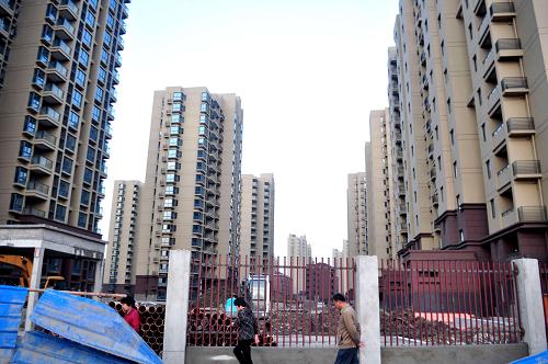 路人從上海顧村大型保障房建設(shè)工地旁經(jīng)過(2011年10月15日攝)。新華社發(fā)(嚴(yán)大明 攝)