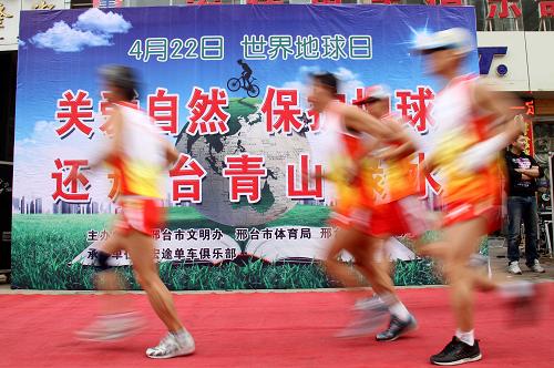 4月22日,河北省邢臺市長跑愛好者從“世界地球日”宣傳板前跑過。當日,河北省邢臺市舉辦“關(guān)愛自然 保護地球 還邢臺青山綠水”世界地球日長跑活動。約100名當?shù)亻L跑愛好者參加了22公里的長跑活動。新華社發(fā)(陳雷 攝)