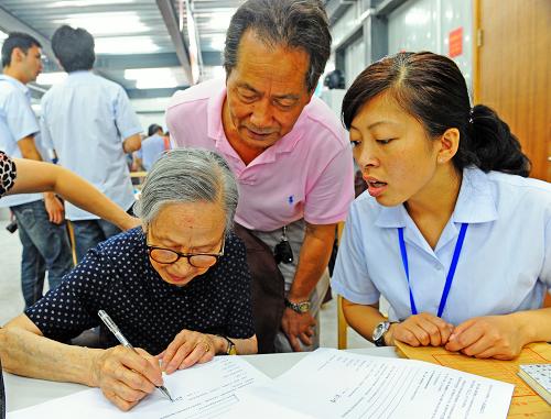 上海黃浦區(qū)露香園路地塊92歲居民俞仁娣(前左)在房屋征收協(xié)議上簽字(2012年6月30日攝)。新華社發(fā)(郭長耀 攝)