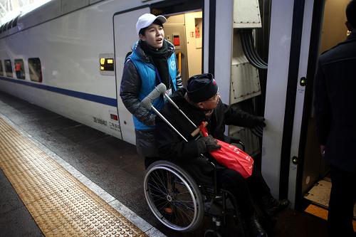 2月3日,北京火車(chē)站的志愿者送行動(dòng)不便的乘客上車(chē)。新華社記者 金立旺 攝