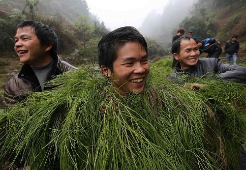 2月28日,在廣西壯族自治區(qū)融水苗族自治縣香粉鄉(xiāng)中坪村茅坪苗寨,兩名村民把編好的芒草披到一名村民身上扮“芒藁”。新華社發(fā)(龍濤 攝)
