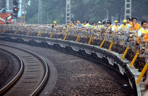 6月23日,滿載石籠的拋石車駛向鄭州黃河大橋。當(dāng)日,一列鐵路專用防洪拋石車駛上京廣鐵路鄭州黃河大橋橋面,鄭州鐵路局鄭州橋工段的100多名工人,將180個(gè)1.6噸的石籠拋進(jìn)河床中心,對(duì)黃河調(diào)水調(diào)沙期間沖刷較為嚴(yán)重10個(gè)橋墩進(jìn)行防護(hù)。始建于1958年的京廣鐵路鄭州黃河大橋位于黃河下游游蕩性河段。為解除每年汛期湍急的黃河水對(duì)大橋橋墩造成的威脅,拋石護(hù)橋工程已經(jīng)進(jìn)行了23年。據(jù)介紹,此次拋石工程將持續(xù)6天時(shí)間,共拋投石塊1080立方米。新華社記者王頌攝