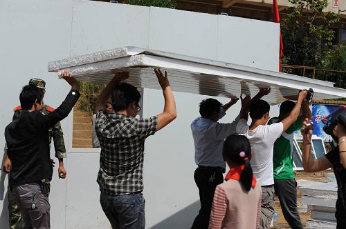 9月10日,云爐小學(xué)教師在搬運(yùn)搭建臨時(shí)教室的材料。當(dāng)日,貴州威寧彝族回族苗族自治縣石門(mén)鄉(xiāng)云爐小學(xué)的教職工在地震災(zāi)區(qū)度過(guò)了一個(gè)特殊的教師節(jié):他們與當(dāng)?shù)剜l(xiāng)村干部和武警官兵一起搭建活動(dòng)板房臨時(shí)教室,確保學(xué)生次日能準(zhǔn)時(shí)上學(xué)。據(jù)該校青年女教師李琳介紹,地震發(fā)生后大家最擔(dān)心的是學(xué)生能不能按時(shí)開(kāi)學(xué)。聽(tīng)說(shuō)政府緊急運(yùn)來(lái)了活動(dòng)板房,學(xué)校的老師一大早都趕來(lái)了。“山里的孩子上學(xué)不容易。我出不了多大的力,但總可以搭上把手,做些小事”,李琳在給武警戰(zhàn)士遞工具、送礦泉水送盒飯的間隙跟記者說(shuō)道。云爐小學(xué)位于貴州烏蒙大山深處。9月7日11時(shí)19分,云南彝良縣與貴州威寧縣交界處發(fā)生5.7級(jí)地震時(shí),全校502名學(xué)生在老師的組織下安全撤離,無(wú)一人傷亡,3所教學(xué)樓中有1所受損。新華社記者 王念 攝