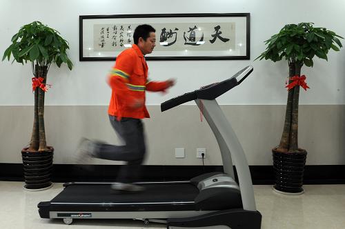10月24日,負(fù)責(zé)駕駛灑水車的環(huán)衛(wèi)工人余國榮利用休息時(shí)間在跑步機(jī)上健身。近日,杭州市西湖區(qū)城管局文新環(huán)衛(wèi)所投入20余萬元建設(shè)的“新杭州人文化家園”正式啟用。這個(gè)利用該所管理用房改造的文化家園包括多媒體教室、健身娛樂室、電子書屋、職工浴室和屋頂露天休閑茶吧等功能區(qū),投影儀、音響、電視機(jī)、乒乓球桌、健身器材等設(shè)備一應(yīng)俱全,集教育、學(xué)習(xí)、健身、娛樂和休閑功能為一體,為豐富100余名大部分由外來務(wù)工人員組成的一線環(huán)衛(wèi)工人及其家屬的業(yè)余文化生活創(chuàng)造了良好條件。