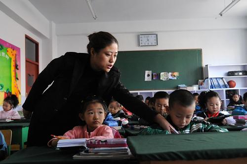 11月15日,鶴崗市東方紅小學(xué)一年級一班的班主任在指導(dǎo)學(xué)生做課前習(xí)字練習(xí)。新華社記者 王凱 攝