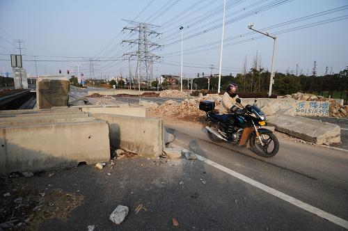 12月25日,一名附近居民騎著摩托車穿過大橋無錫段入口處的路障。新華社記者 沈鵬攝