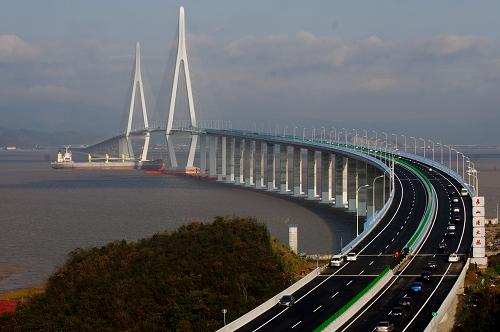 12月28日,車輛從寧波象山港跨海大橋上通過,此時一艘大型貨輪從橋下通航而過。新華社記者 黃宗治攝