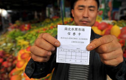 12月28日,??谑心媳彼袌龅墓ぷ魅藛T展示市場信譽(yù)卡。新華社記者 郭程 攝