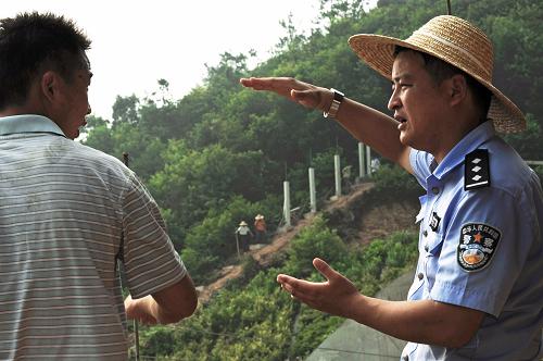 在寧杭高鐵浙江段一處隧道口的山坡上,浙江德清鐵路派出所警官程飛(右)在與一位施工負(fù)責(zé)人討論高鐵防護(hù)柵欄的合理布局(7月19日攝)。新華社記者 譚進(jìn) 攝