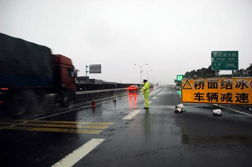 12月29日,在鄱陽(yáng)湖大橋邊,交警在結(jié)冰路面執(zhí)勤,橋面設(shè)置了圓錐筒減道壓速。新華社記者 劉彬攝