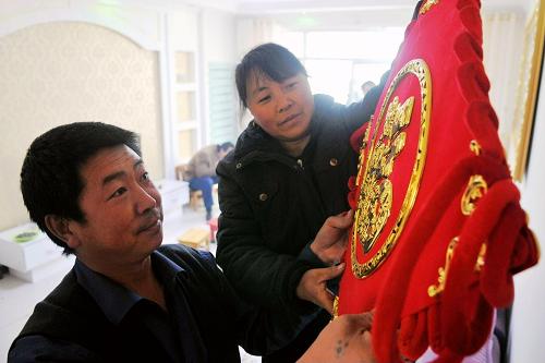 12月29日,剛剛喬遷新居的村民張?zhí)K安(左)和妻子一起將“福”字中國結(jié)掛在墻上。曾被“8·8”特大山洪泥石流災(zāi)害重創(chuàng)的甘肅舟曲縣城如今已舊貌換新顏。2年時間,19棟高樓組成的小區(qū)取代了羅家峪的殘垣斷壁,所有樓房都配備了可視門禁系統(tǒng)、有線電視、網(wǎng)線、電話等,水、電、天然氣等設(shè)施也全部實(shí)現(xiàn)了智能卡控制。據(jù)了解,舟曲3580套分配到戶的災(zāi)民安置房里目前大多都在裝修或者已經(jīng)入住。今年底,舟曲城鄉(xiāng)住房、公共服務(wù)和基礎(chǔ)設(shè)施等各項(xiàng)恢復(fù)重建項(xiàng)目已全部完成并投入使用,災(zāi)區(qū)基本生產(chǎn)生活條件和經(jīng)濟(jì)社會發(fā)展已全面恢復(fù),一個新舟曲正在崛起。新華社記者 陳斌 攝