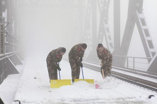 1月12日,遼寧丹東邊防檢查站官兵在中朝友誼橋上清除積雪。新華社發(fā)(吳瓊 攝)