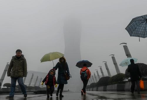 1月13日,行人冒雨走在霧霾籠罩下的杭州市區(qū)的一個(gè)廣場(chǎng)附近。新華社記者 韓傳號(hào) 攝
