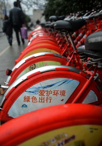 1月14日,杭州市民走過市區(qū)一個公共自行車租賃點。 新華社記者 韓傳號 攝