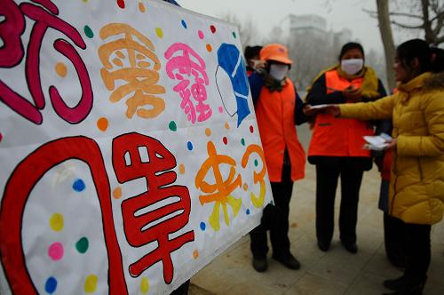 1月15日,山東聊城大學(xué)生命科學(xué)學(xué)院的大學(xué)生愛心志愿者在為環(huán)衛(wèi)工人發(fā)放口罩和應(yīng)對(duì)霧霾天氣的小知識(shí)宣傳單。新華社發(fā)(張振祥 攝)