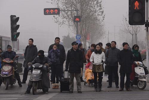 1月15日,在鄭州市霧霾彌漫的街頭,行人等待過馬路。 新華社記者 趙鵬 攝