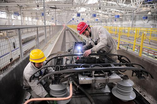 1月18日,兩名動車所地勤機械師在車頂檢修動車組受電弓。新華社發(fā)(唐振江 攝)