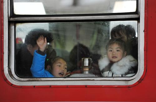 2月8日,在南昌開往揚州的列車上,兩位小朋友正在向車窗外的親人告別。新華社記者 彭昭之 攝