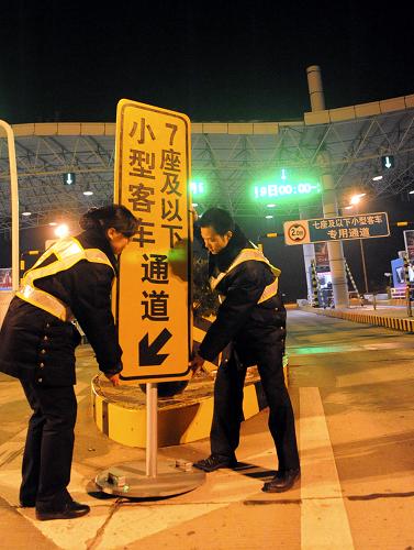 2月9日零時過后,啟揚高速公路揚州段揚州西收費站工作人員在調(diào)整小型客車通道指示牌。新華社發(fā)(莊文斌 攝)