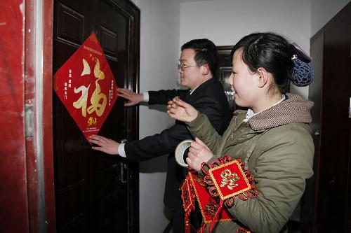 2月7日,山東省滕州市一回遷小區(qū)物業(yè)管理人員給回遷戶大門貼福字。新華社發(fā)(宋海存 攝)
