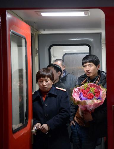 2月14日,在南昌火車(chē)站,一位捧著玫瑰花的小伙子站在硬座車(chē)廂連接處,他將站立四個(gè)多小時(shí)前往贛州與女朋友見(jiàn)面。新華社記者周密攝