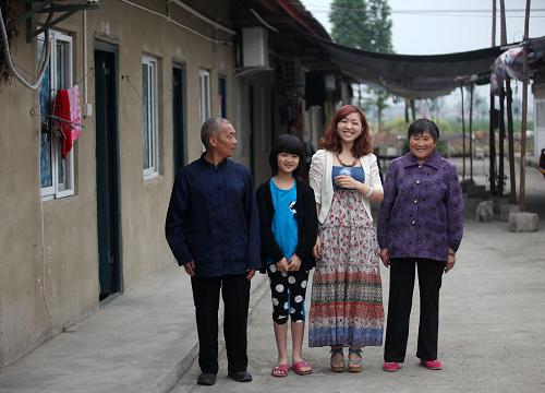 震后五年,因新建的永久性住房離化肥廠很近,梁正彬父母選擇繼續(xù)在什邡市南泉鎮(zhèn)的過渡房居住,這是他們家人在過渡房前合影(2013年5月1日攝)。 采訪節(jié)點:2008年、2009年、2011年、2013年 家庭成員:梁正彬(38歲)、唐智慧(31歲)、梁詠琪(9歲)等 家庭現(xiàn)狀:唐智慧夫婦帶著上學的女兒在什邡市區(qū)租了房子,公婆仍住在位于什邡市南泉鎮(zhèn)的安置區(qū)里。 2013年4月30日,當記者在四川德陽什邡市區(qū)見到唐智慧時,和兩年前相比,這個已過而立之年的媽媽看起來仍然十分漂亮。 汶川地震后,唐智慧和丈夫梁正彬在鎣華鎮(zhèn)仁和村的小家被震垮。兩人從廢墟里面費了不小的勁兒才扒出結婚照,這一幸福的瞬間恰巧被路過的攝影師記錄了下來。 唐智慧說,女兒梁詠琪目前在什邡市區(qū)的北京小學讀書,為了方便照顧孩子,他們夫妻倆就在學校附近租了房子,婆婆平時也在這里照看,只有周末時,婆婆才帶著孩子回到他們已經(jīng)住了三四年的安置區(qū)里,孩子的爺爺仍在那里居住。 位于什邡市南泉鎮(zhèn)的安置區(qū)如今略顯冷清。“大多數(shù)人都不在這里住了”,唐智慧說,“有些人是迫于生計,