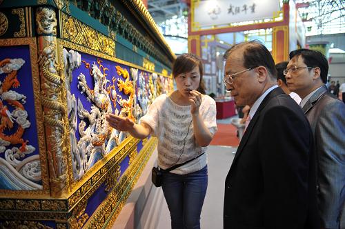 5月18日,在河北省廊坊市國際會展中心,工作人員(左一)向客商介紹滕氏布糊畫。新華社發(fā)(朱旭東 攝)