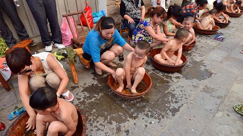 6月7日,在秭歸縣歸州鎮(zhèn)屈子街,年輕父母為孩子們洗艾葉浴,希望他們健康成長。新華社發(fā)(鄭家裕 攝)