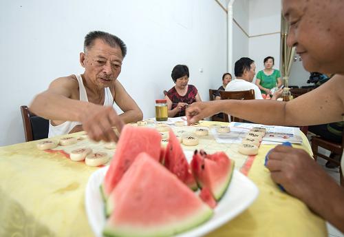 6月19日,武漢市百步亭社區(qū)悅秀苑的老年人在納涼點下棋娛樂。新華社記者 程敏 攝