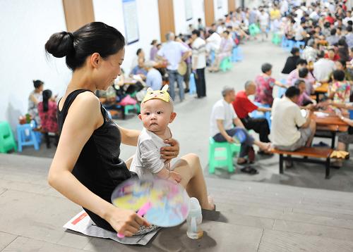 6月19日,一名婦女在重慶市渝北區(qū)大龍山人防工程納涼點(diǎn)內(nèi)扇著扇子為懷中的嬰兒祛暑降溫。新華社記者 劉潺 攝