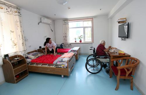 6月19日,一位工作人員(左)幫助正在吃午飯的老人整理房間。新華社發(fā)(劉東岳 攝)