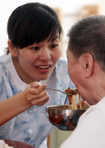 6月19日,一位工作人員(左)在為老人喂飯。新華社發(fā)(劉東岳 攝)