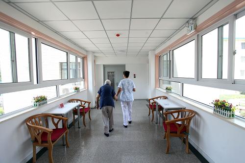6月19日,一位老人(左)在工作人員的帶領(lǐng)下走過中心明亮的通道。新華社發(fā)(劉東岳 攝)