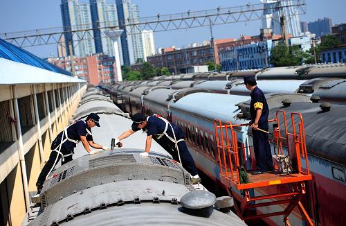 8月1日,站在2米多高的列車頂部,武漢鐵路局武昌客車車輛段客車整備場(chǎng)工作人員包鋒(中)和呂淳(左)站在僅容一人下腳的空調(diào)機(jī)組左右兩端,用電動(dòng)扳手嫻熟地開啟著密密麻麻的螺絲。新華社記者 肖藝九攝