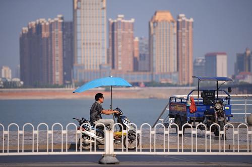 江西南昌街頭,市民們在烈日下騎著帶有陽傘的電動車(7月31日攝)。連日的高溫天氣籠罩江西,卻帶動了當?shù)仉妱榆囌陉杺闶袌觥_@種遮陽傘用一根金屬棍固定在電動車上,剛好能遮住騎車人頭頂?shù)年柟?。?jù)安裝商家介紹,這種電動車遮陽傘價格在60元左右,安裝起來也很簡單,在今夏炎熱的天氣里極受歡迎。但據(jù)交警部門介紹,這樣的遮陽傘由于產(chǎn)生風阻,從而干擾車輛方向,因此并不鼓勵市民安裝類似的遮陽傘。新華社記者周密攝