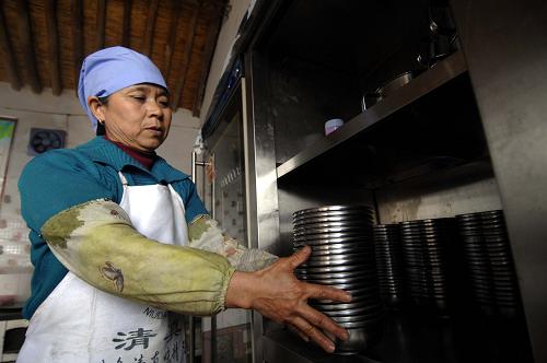 12月5日,朱套小學(xué)定點托餐農(nóng)戶正在把孩子們用完的餐具清洗消毒后放進(jìn)家中專門的碗柜。 從2011年秋季學(xué)期起,國家正式啟動民族縣、貧困縣農(nóng)村免費午餐試點工作,寧夏回族自治區(qū)固原市原州區(qū)、西吉縣、隆德縣、涇源縣、彭陽縣、紅寺堡區(qū)、鹽池縣、同心縣、海原縣部分農(nóng)村小學(xué)作為首批試點小學(xué),從8月30日正式開始免費午餐計劃,試點受益學(xué)生約2萬名,自治區(qū)財政共撥付資金1200萬余元。如今,秋季學(xué)期即將結(jié)束,免費午餐計劃已經(jīng)在這些試點小學(xué)內(nèi)實行了3個多月了,孩子們的免費午餐到底怎么樣,記者來到位于寧夏中部干旱帶的海原縣賈塘鄉(xiāng)朱套小學(xué),用鏡頭記錄下旱區(qū)兒童的免費午餐。 朱套小學(xué)現(xiàn)有在校學(xué)生104名,由于貧困和常年干旱缺水、學(xué)校條件有限等原因,學(xué)校采取農(nóng)戶定點托餐的供餐形式,每天由學(xué)校附近的鄉(xiāng)村農(nóng)戶準(zhǔn)備學(xué)生們的免費午餐,托餐點定期接受衛(wèi)生監(jiān)督檢查。 “今年這個免費午餐實施以后,孩子們特別愛吃,家長也高興,有時候也來學(xué)校查,看孩子是怎樣吃的,大人是怎樣做的,菜的味道等,結(jié)果讓家長非常高興。” 賈塘鄉(xiāng)朱套小學(xué)老師田進(jìn)龍說。 據(jù)了解,免費午餐計劃從2012年春季學(xué)期起將在山區(qū)九縣區(qū)所有農(nóng)