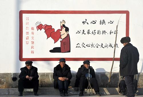 寧夏中衛(wèi)市沙坡頭區(qū)鎮(zhèn)羅鎮(zhèn)河溝村幾名村民坐在村里的文化墻前曬太陽(1月31日攝)。新華社記者 彭昭之 攝