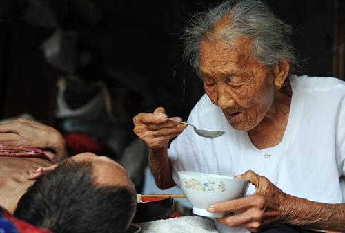 2011年8月18日,許張氏把湯吹涼喂兒子吃。安徽省亳州市譙城區(qū)95歲老人許張氏照顧病兒40余年,在平凡的飲食起居中詮釋著偉大的母愛,引發(fā)社會民眾廣泛關(guān)注,感動了億萬網(wǎng)民,許張氏也被網(wǎng)民譽為“最堅強母親”。 新華社發(fā)