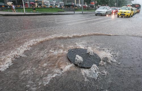 7月12日,重慶市渝北區(qū),路面窨井蓋向外涌水,造成路面積水。新華社記者 陳誠 攝